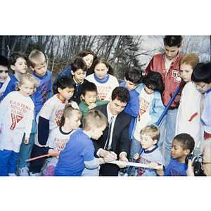 Children watching a man sign a hockey stick outside the Eastern Middlesex Family YMCA