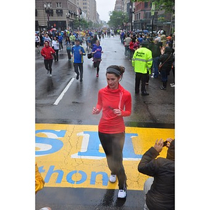 Woman walks through One Run finish line as a spectator takes pictures