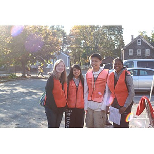 Teen volunteers wearing orange safety vests pose for picture
