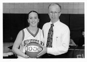 Suffolk University women's basketball player Kate Norton receives basketball from Coach Ed Leyden commemorating her reaching 1,000 career points mark, circa 1999