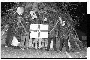 Hooded Loyalists in front of bonfire and flag, Bridge Street, Downpatrick on the eve of the 12th of July. Just before the fire was lit