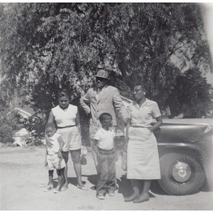 A family poses in a dirt driveway