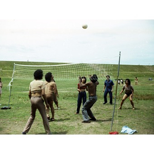Three women and four men play volleyball at a La Alianza Hispana staff picnic.