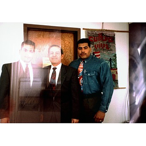 Three men in suits and ties pose for a portrait in front of the Cultura Viva banner in the Inquilinos Boricuas en Acción offices.