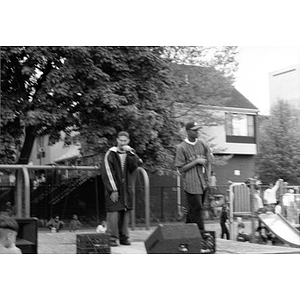 Two young men perform on an outdoor stage in Villa Victoria neighborhood.