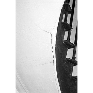 Cracked plaster underneath a staircase.