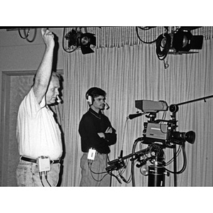 Adult and young man operating video recording equipment.