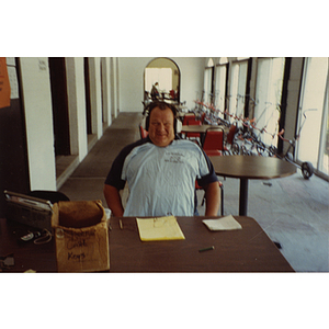 A man seated at a table with a t-shirt over his chest at a Boys and Girls Club Golf Tournament