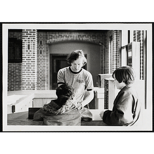 Two boys, facing away from the camera, stand in front of a male staff member