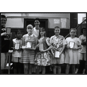 Heather Khan, a former news anchor, posing with six boys and girls holding their awards at a Kiwanis Awards Night