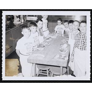 Members of the Tom Pappas Chefs' Club pose with plates of food in a kitchen