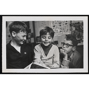 Three boys read a book