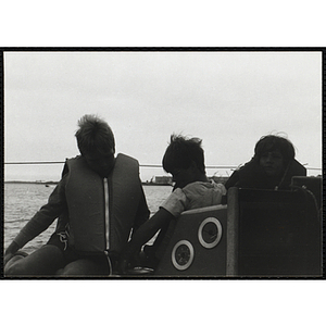 A Group of three boys sitting next to the cabin on a sailboat