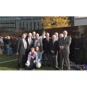 Several people pose together in front of the Veterans Memorial at the dedication ceremony