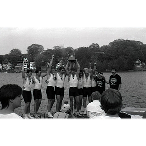 Victorious men's crew team holding a trophy on the Charles River