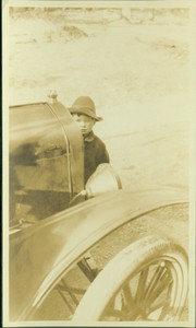 Unidentified boy standing in front of an automobile on the grounds of the Lyman Estate, Waltham, Mass.