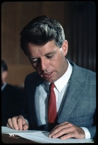 Bobby Kennedy, seated at a desk, reading