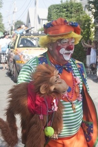 Parade marcher dressed as a clown with a monkey puppet : Provincetown Carnival parade