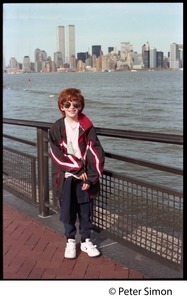 Child standing by the water, with Manhattan and the World Trade Center towers in the background