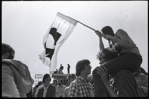 Antiwar demonstration at Fort Dix, N.J.: woman on shoulder of fellow protester, waving flag for draft resistance (with omega symbol)