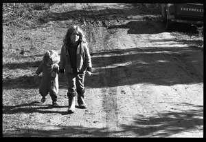 Young girl leading a toddler by hand down a muddy road, Earth People's Park