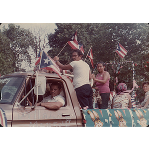 People stand in a pick-up truck with Puerto Rican flags