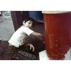 Little boy painting a column bright red.