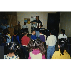 Man playing an accordion for children at an after-school program.