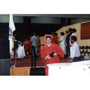 Young man in red cap and gown at a graduation ceremony.