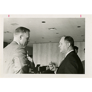 Two men stand and converse at a Boys' Club meeting