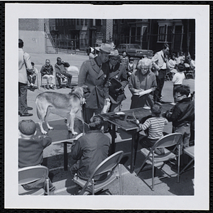 Three judges stand together and interview a participant while others look on during a Boys' Club Pet Show
