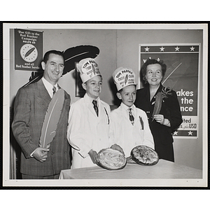 Two members of the Tom Pappas Chefs' Club pose with pies along an unidentified woman and man holding large feathers