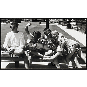 Group of children sitting on a bench next to a counselor