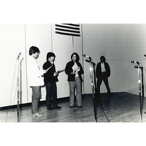 Four people stand onstage performing a theatrical sketch at the Josiah Quincy School about the normalization of U.S. and China relations