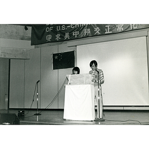 Chinese man and woman stand at the podium in the Josiah Quincy School auditorium at an event about the normalization of U.S. and China relations