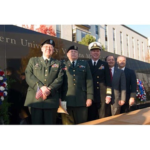 Five men, three in military dress, pose with the Veterans Memorial at the dedication ceremony