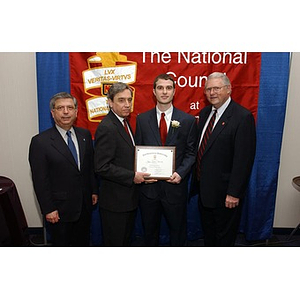 Joshua Seadia poses with his certificate and three men at the National Council Dinner