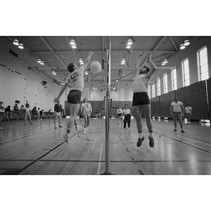 Two volleyball players jump in the air during intramural volleyball in Dockser Gym