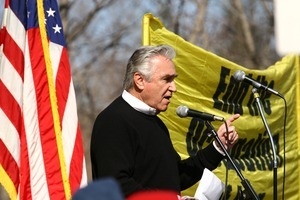 Congressman Maurice D. Hinchey at the microphone, addressing protesters, with American flag and 'End the occupation' banner in background: rally and march against the Iraq War