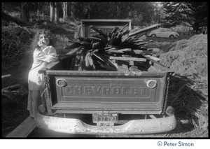 Usha (Cathy Brown) leaning on the back of a pickup truck filled with scrap wood