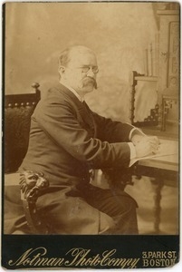 Charles H. Litchman: three-quarter length studio portrait, seated at desk, writing