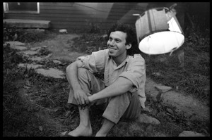 Tom Fels, seated on the ground in front of the house, Montague Farm Commune (double exposure)