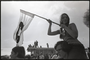 Antiwar demonstration at Fort Dix, N.J.: woman in shoulders of fellow protester waving flag for draft resistance (with omega symbol)