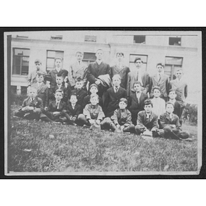 Group of young men and boys pose together on a grassy lawn
