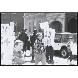 Several boys and girls marching down the street with their signs during the Boys and Girls Clubs of Boston 100th Anniversary Celebration Parade