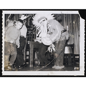 Boys dance on a stage with a man dressed in Native American costume