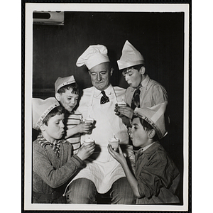 Members of the Tom Pappas Chefs' Club hold cupcakes as they surround an unidentified man