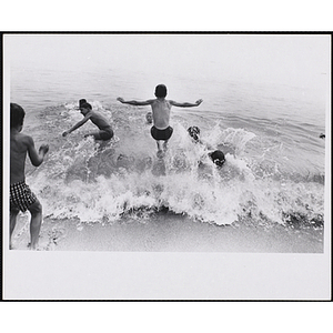 A group of boys swim in the surf on a beach
