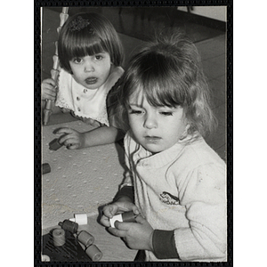 Two girls sitting at a table and playing with stacking toys