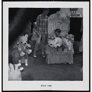 Marianne Connolley, Miss South Boston of 1968, sitting on her throne with a stuffed animal while her brother looks on during a Boys' Club Little Sister Contest